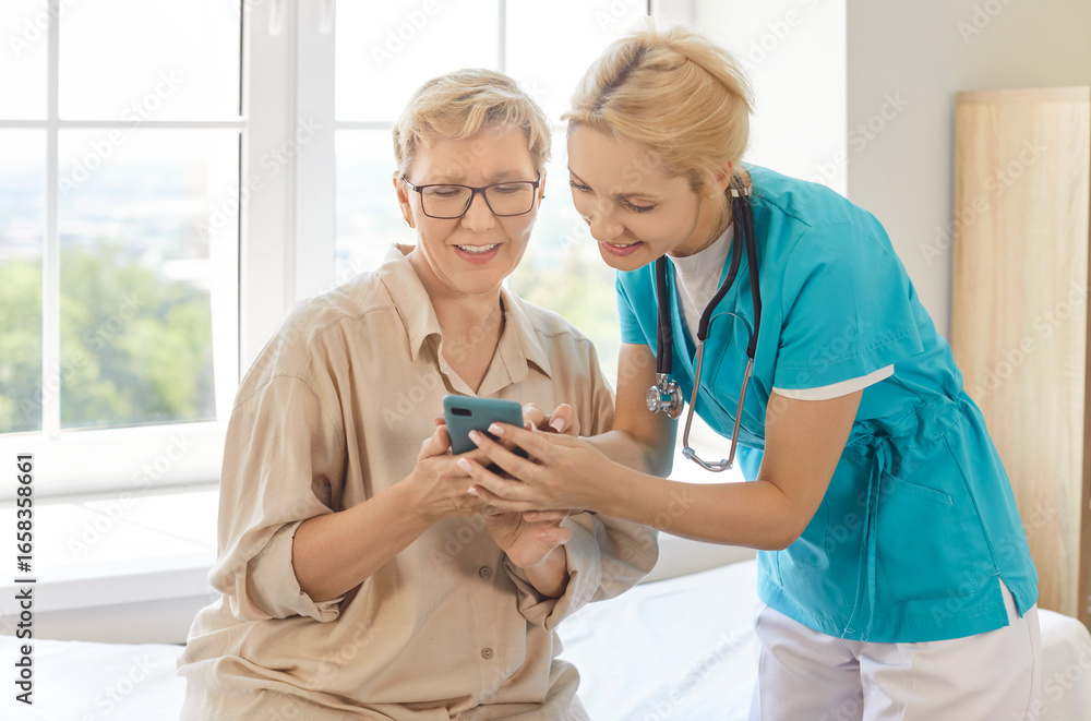 Nurse or caregiver helping elderly woman with usage of smartphone, downloading app for monitoring health, posing in clinic or health centre. Professional guidance and health care concept