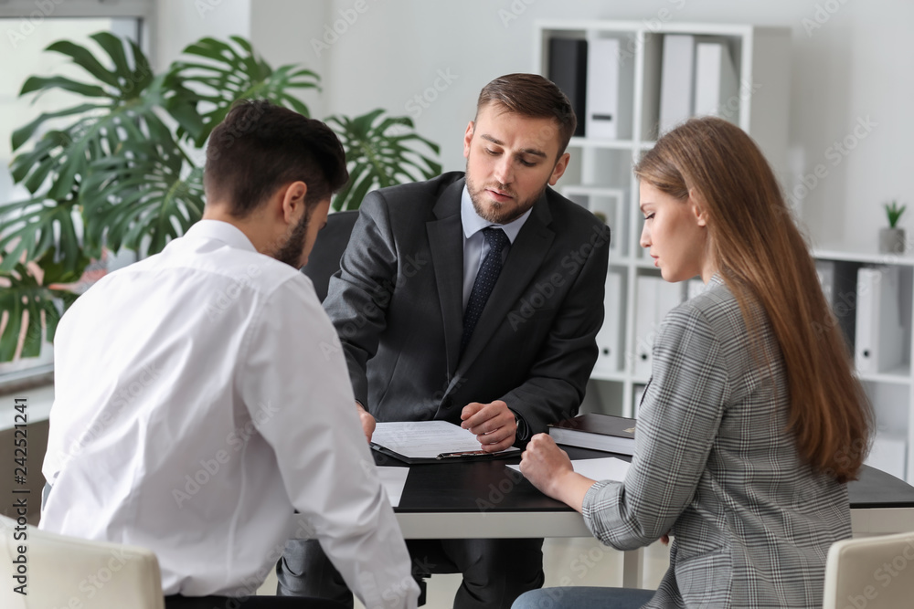 Unhappy young couple visiting divorce lawyer in office