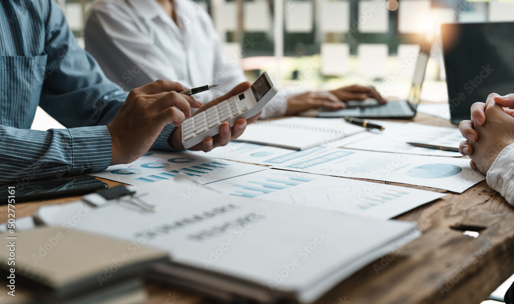 Accountant or bookkeeper working with calculator to calculate business data summary report, accountancy document and laptop computer at office, business meeting concept