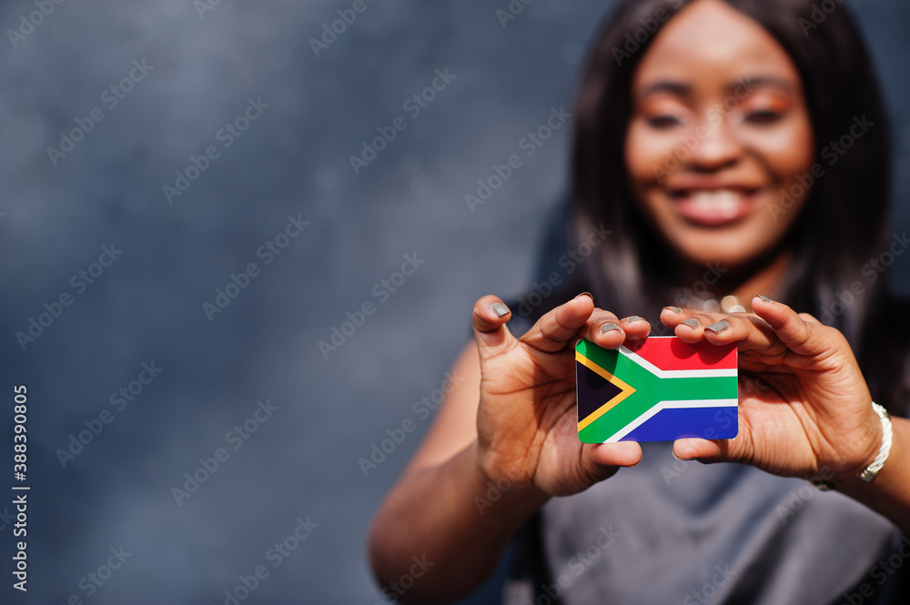 African woman hold small South Africa flag in hands.