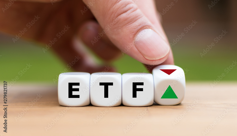 Hand is turning a dice and changes the direction of an arrow symbolizing that the value of an ETF (Exchange Traded Fund) is going up (or vice versa)