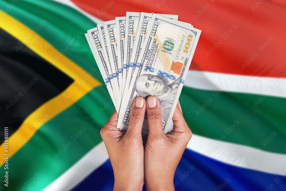 South Africa financial concept. Female hand holding dollar banknotes on national flag background. Currency and money theme with copy space.